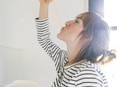 Spain, Barcelona, Barcelona, Women eating and holding a pasta strainer ready to cook a recipe, pasta italian  cooking recipe  women caucasian modern-kitchen sunny-day striped-top